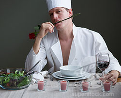 A man in a chefs outfit with a rose in his mouth